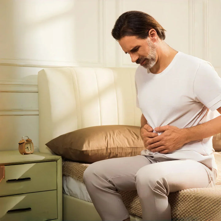 man sitting on a bed with abdominal discomfort