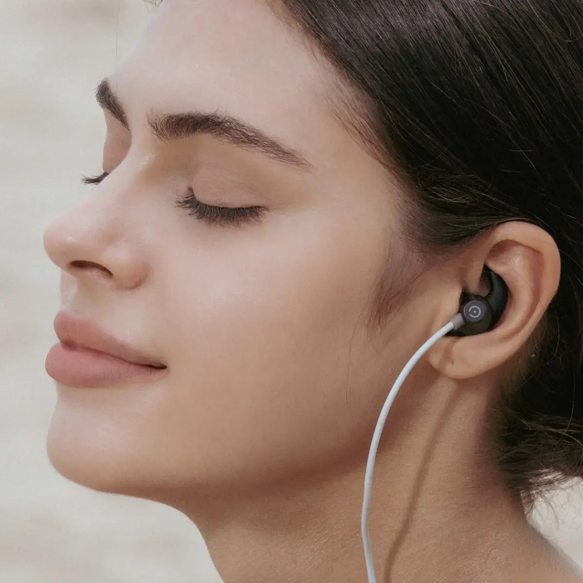 Woman using an ear-worn vagus nerve stimulation device during a calm wellness routine