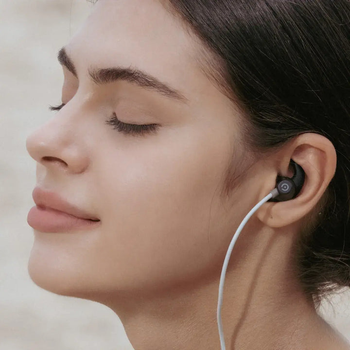 Woman using an ear-worn vagus nerve stimulation device during a calm wellness routine