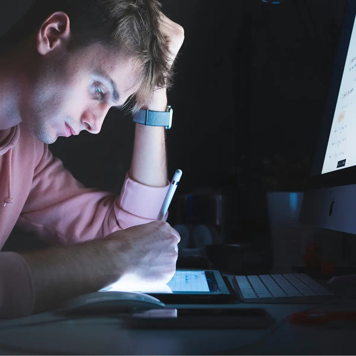 A person struggling to concentrate while working at a desk in a modern office environment